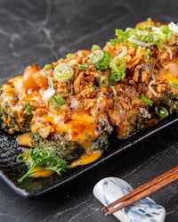 japanese food on a black plate with chopsticks