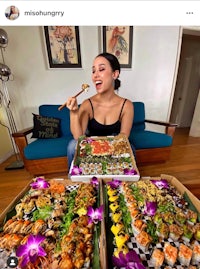 a woman sitting on a couch eating sushi