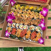 a box of sushi is sitting on a wooden table